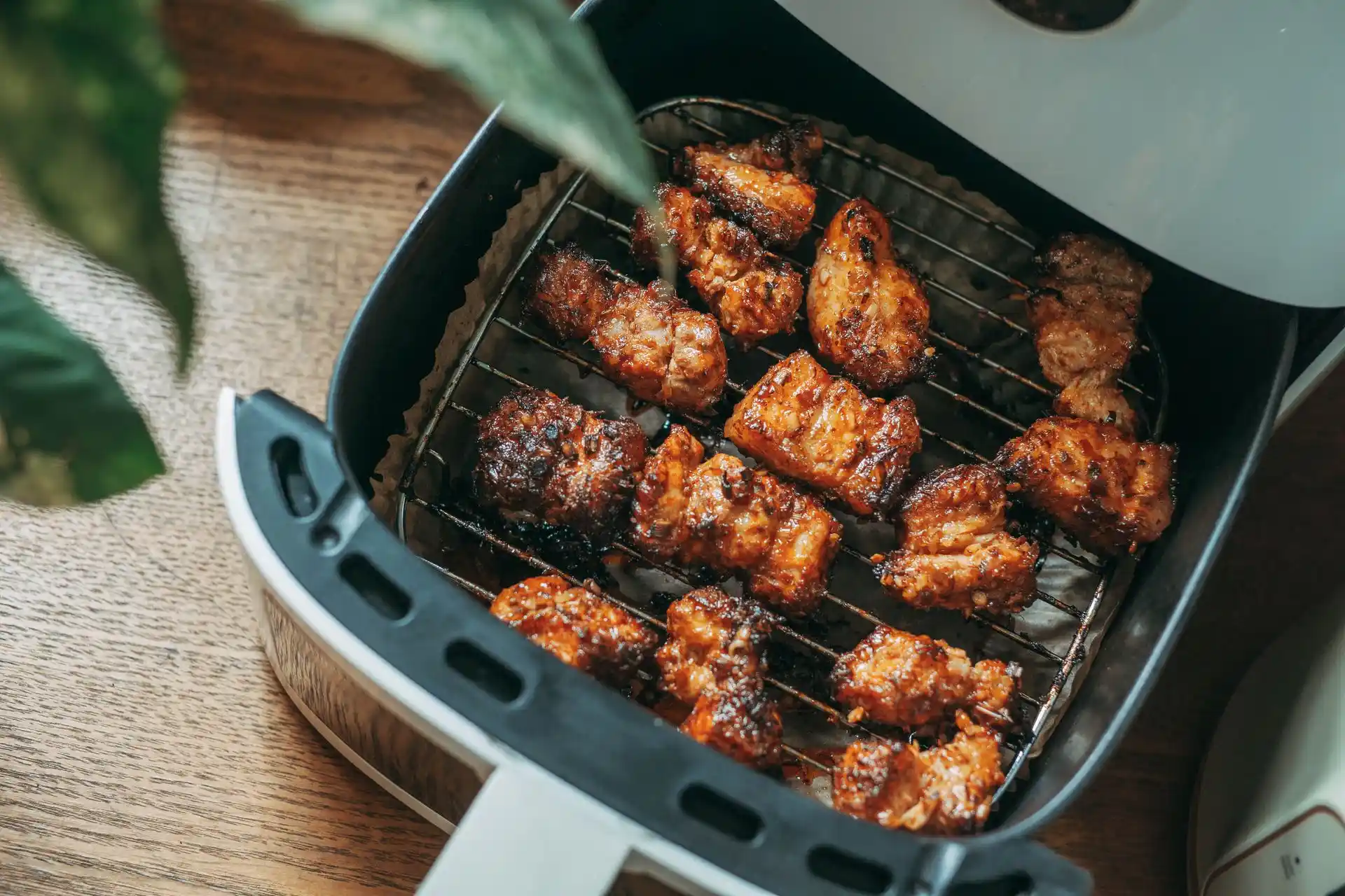 An open air fryer with a clean basket, sponge, and dish soap on a kitchen counter ready for cleaning